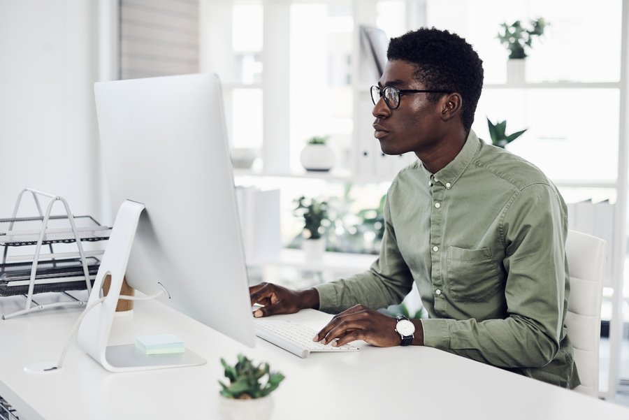 Jovem em frente ao computador em busca de formas de economizar energia no trabalho remoto sustentável. 